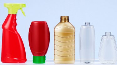 Das Bild zeigt fünf unterschiedlich geformte Kunststoffflaschen in verschiedenen Farben, darunter rote, goldene und transparente Flaschen, die für unterschiedliche Verwendungszwecke wie Sprüh- und Lebensmittelbehälter geeignet sind.