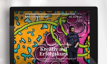 Das Bild zeigt ein Tablet mit einer geöffneten digitalen Zeitschrift der KHS, die den Titel "Kreativ auf Erfolgskurs" trägt, im Hintergrund eine bunte Graffiti-Wand.